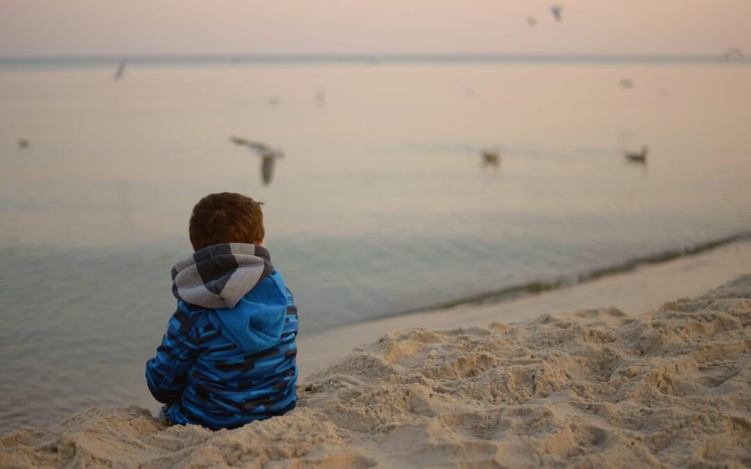 Imagen de un niño sentado en una playa, a modo figurativo del trauma oculto.